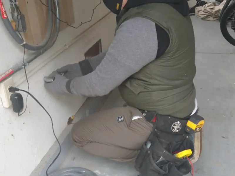 Electrician performing outlet wiring in a Warrington garage
